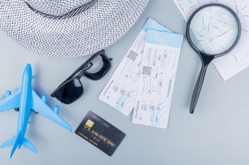 top view of travel accessories and items such as sunglasses sunhat plane tickets blue model plane